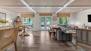 Un amplio salón con techo de madera, un sofá, una mesa de comedor y un televisor montado en la pared.