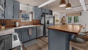 Una cocina moderna con gabinetes grises, electrodomésticos de acero inoxidable y una isla de madera.