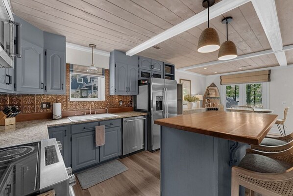 A modern kitchen with grey cabinets, stainless steel appliances, and a wooden island.