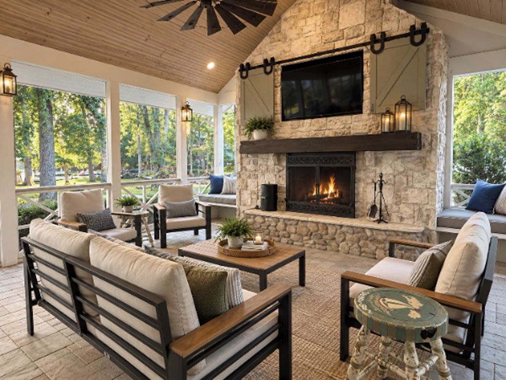 A stone fireplace with a flat-screen TV above it, surrounded by seating and a ceiling fan.