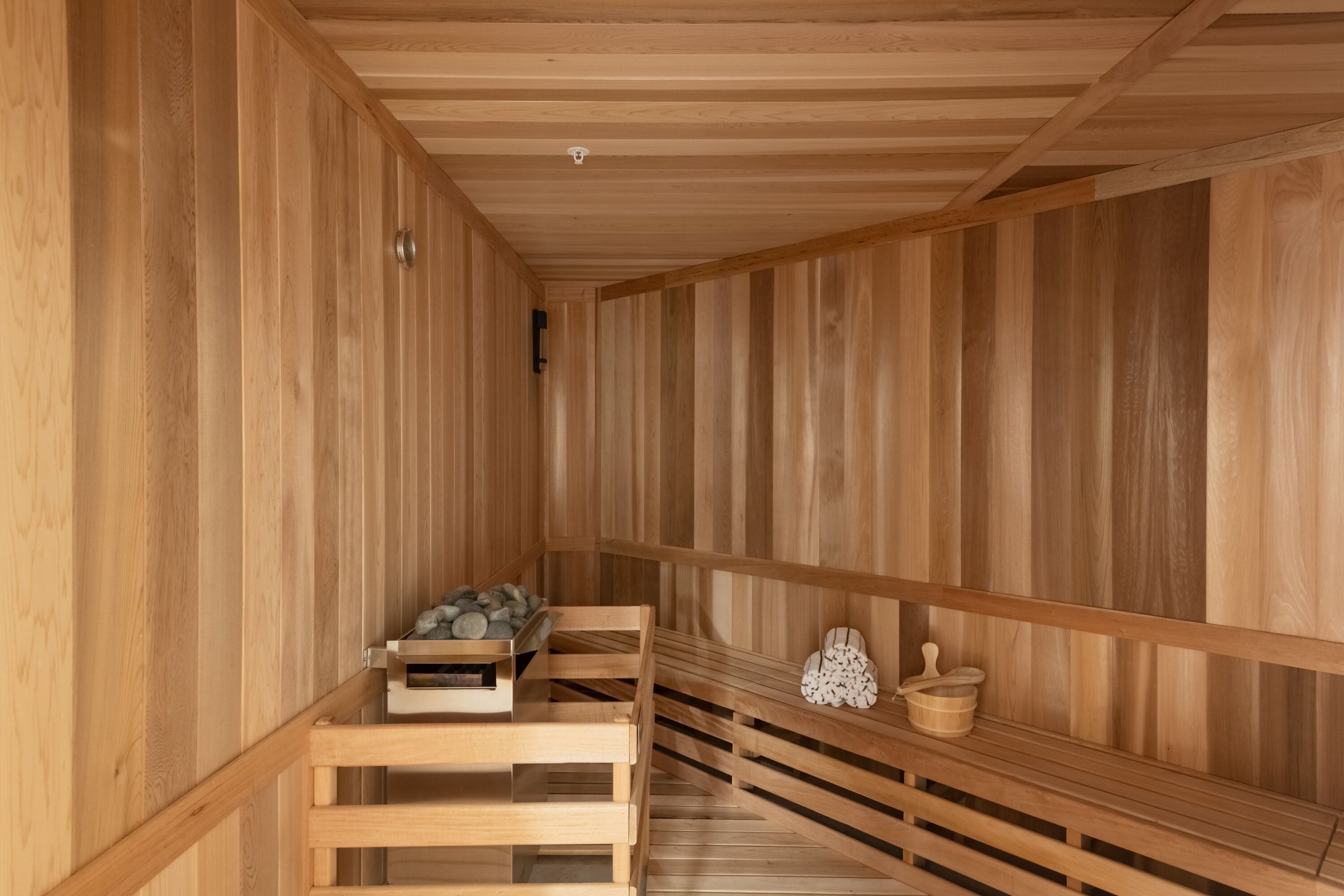 A wooden sauna with benches and a small table with towels.