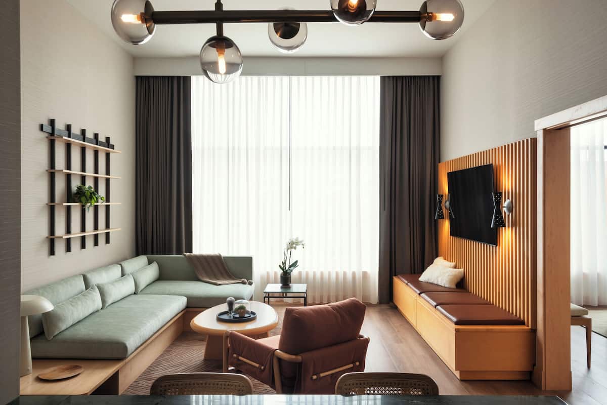 A modern living room with a sofa, armchair, and a TV mounted on a wooden wall.
