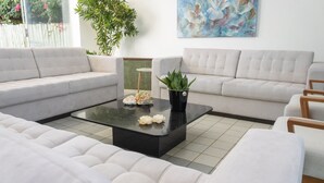 A modern living room with a sectional sofa, a glass coffee table with decorative items, and a potted plant.