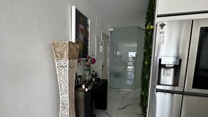 Une cuisine moderne dotée d’un réfrigérateur en acier inoxydable, d’un distributeur d’eau et d’un vase décoratif orné de fleurs.