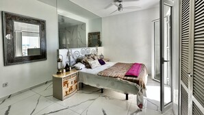 Une chambre à coucher avec un lit, une commode, un miroir et un ventilateur de plafond.