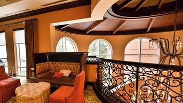 A spacious living area with a curved balcony, a sofa, ottoman, and a chair.
