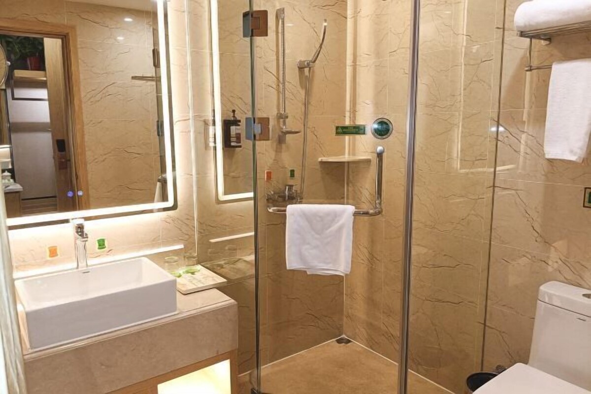 A modern bathroom with a glass-enclosed shower, a large mirror, and a white sink.