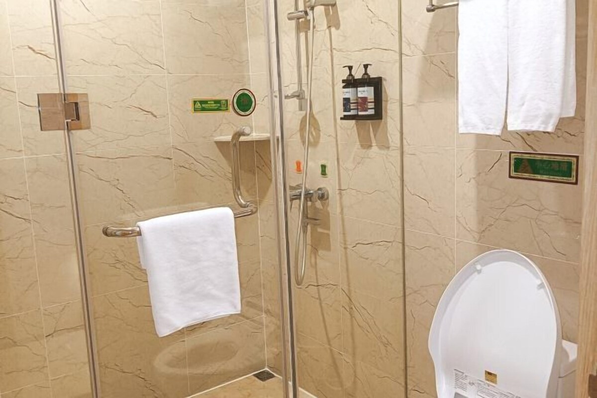 Un baño con ducha envuelta en vidrio, inodoro y perchero para toallas.