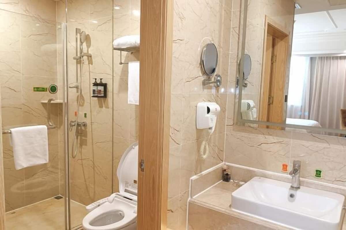 Une salle de bain moderne avec une douche à parois de verre, des toilettes et un lavabo surmonté d’un miroir.