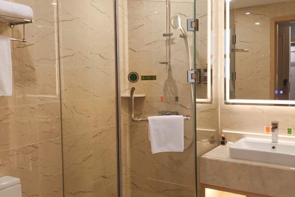 A modern bathroom with a glass-enclosed shower, a white sink, and a marble-tiled wall.