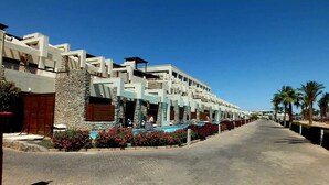 A row of modern, multi-story buildings with balconies, a swimming pool, and palm trees. - Panoramic Romantic apartment  (South Sinai Governorate)