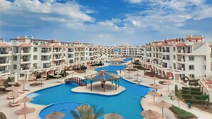 A resort with multiple white buildings, a central swimming pool, and surrounding lounge areas. - Panoramic Romantic apartment  (South Sinai Governorate)