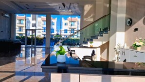 A modern lobby with a glass wall, a reception desk, and a staircase. - Panoramic Romantic apartment  (South Sinai Governorate)