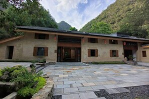 A traditional building with a stone-paved entrance, surrounded by greenery and mountains. - Geya Sigu Health Holiday Hotel (Nandan)