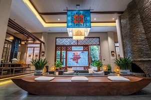 Un área de recepción con mostrador, asientos, una pared decorativa con caracteres chinos y un letrero colgante.