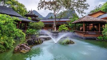 A traditional courtyard with a water feature, pavilions, and lush greenery.
