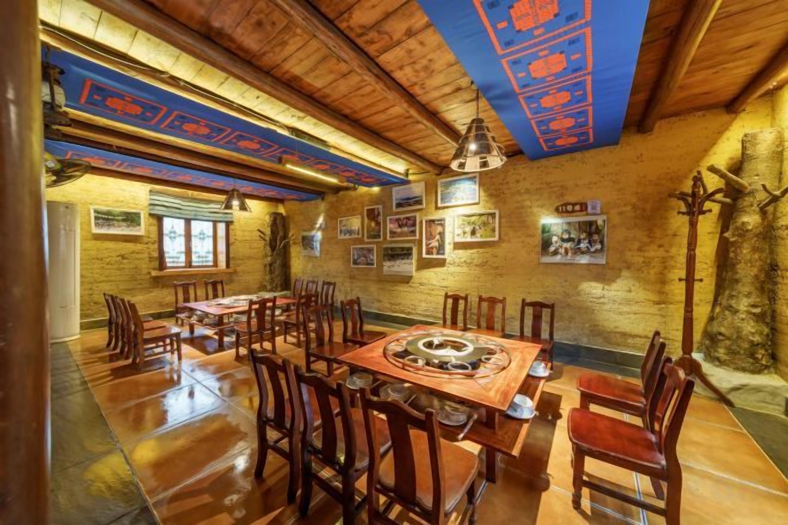 Un restaurante con mesas y sillas de madera, una amplia mesa central con un centro de mesa decorativo y una pared de piedra rústica.