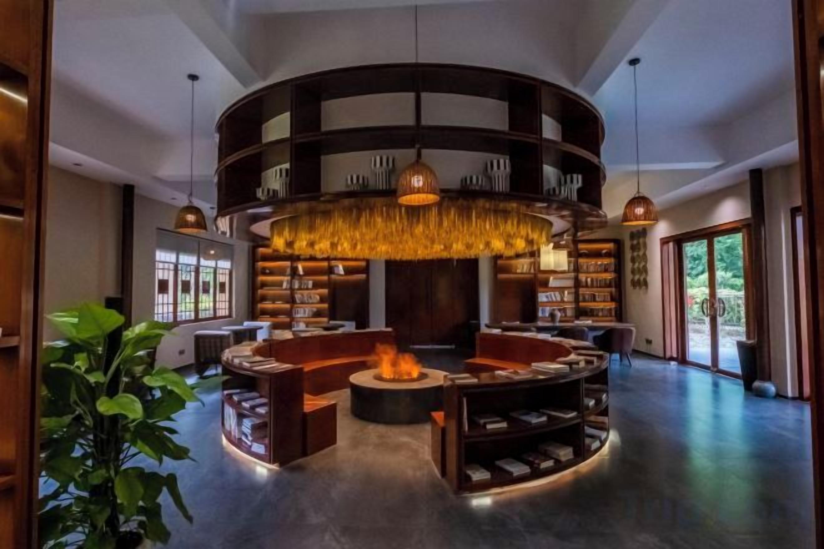A modern interior with a circular seating area, bookshelves, and a central fire feature.