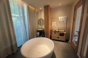 A modern bathroom with a large freestanding bathtub, a wooden vanity, and a mirror. - Geya Sigu Health Holiday Hotel (Nandan)