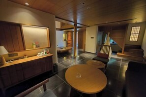 A modern interior with a wooden dining table, a sofa, and a bench. There is a kitchen area with a counter and cabinets. - Geya Sigu Health Holiday Hotel (Nandan)