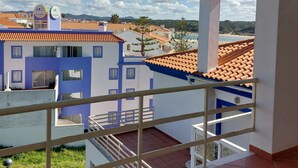 A balcony with a view of a town, including a blue and white building with a sign that reads "DunaMar." - 2 bedrooms beachfront (Vila Nova de Milfontes)