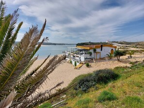 A coastal building with a beach view, a patio area, and a small garden. - 2-bedroom apartment right on the beach (Vila Nova de Milfontes)