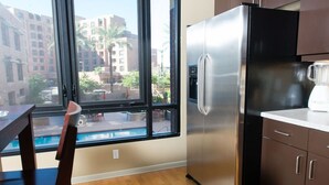 A kitchen with a stainless steel refrigerator, wooden flooring, and a view of a swimming pool through large windows. - 7301 E. 3rd Avenue / UNIT #208 (Scottsdale)
