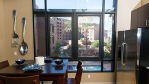 A modern kitchen with a large window, stainless steel appliances, and a dining area with wooden furniture. - 7301 E. 3rd Avenue / UNIT #208 (Scottsdale)