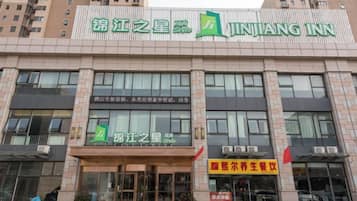 En bygning med et skilt for 'JINJIANG INN' og et mindre skilt for 'JINJIANG'S STAR HOTEL'.