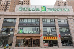 A building with a sign for 'JINJIANG INN' and a smaller sign for 'JINJIANG'S STAR HOTEL'. - Jinjiang Inn Wuqing Traditional Chinese Medical Hospital Hotel Tianjin (Tianjin)