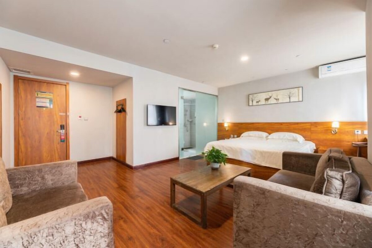 A hotel room with a bed, a sofa, a coffee table, and a TV.
