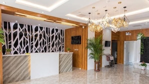 A reception area with a marble floor, wooden reception desk, modern lighting, and a large potted plant. - Jinjiang Inn Wuqing Traditional Chinese Medical Hospital Hotel Tianjin (Tianjin)