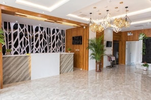 A reception area with a marble floor, wooden reception desk, modern lighting, and a large potted plant. - Jinjiang Inn Wuqing Traditional Chinese Medical Hospital Hotel Tianjin (Tianjin)
