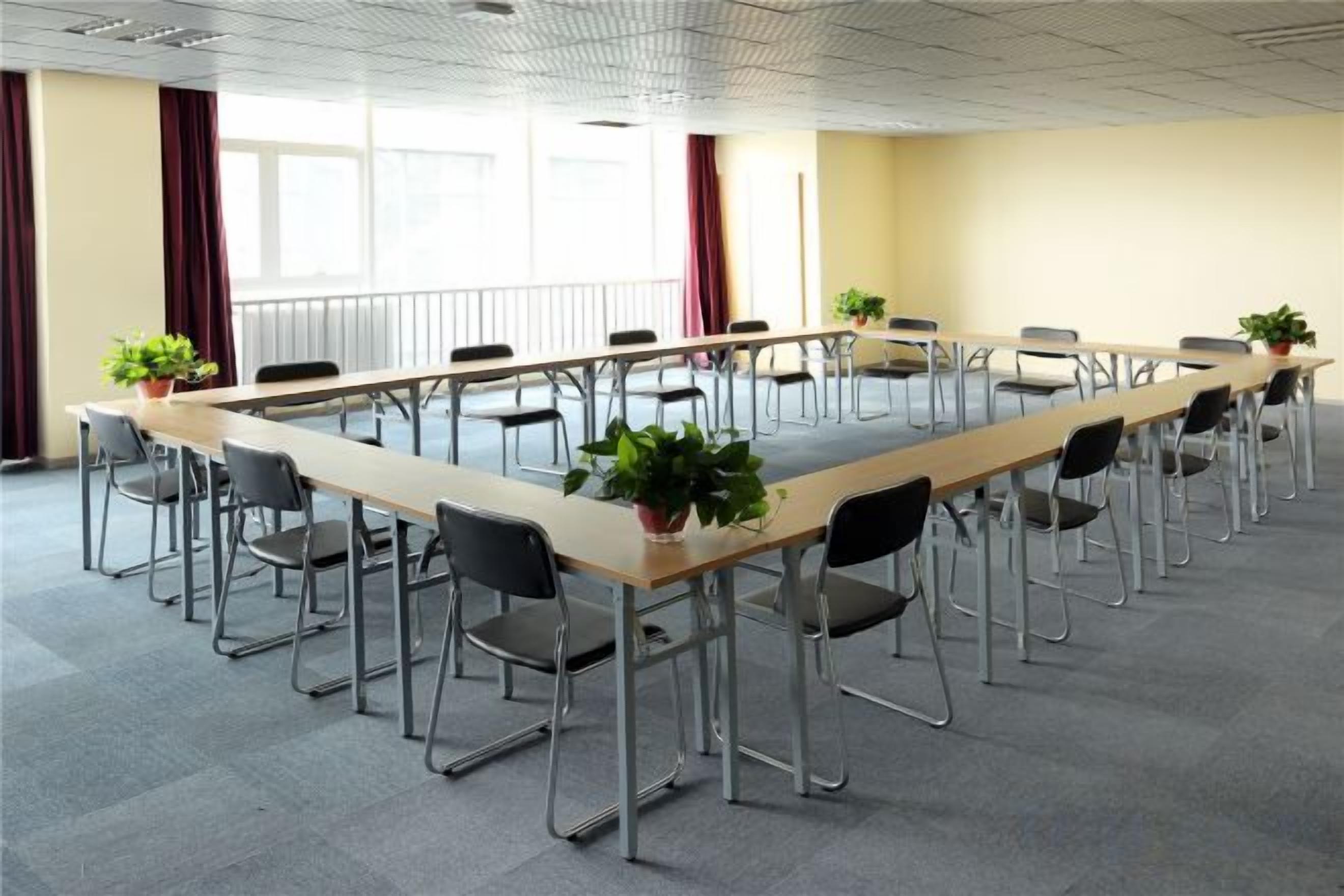 Ein Konferenzraum mit einem langen Tisch, Stühlen und Zimmerpflanzen.
