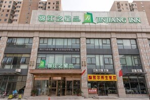 Ein Hotel mit gut sichtbarer Beschilderung für 'JINJIANG INN' und einem gut erkennbaren Eingang.