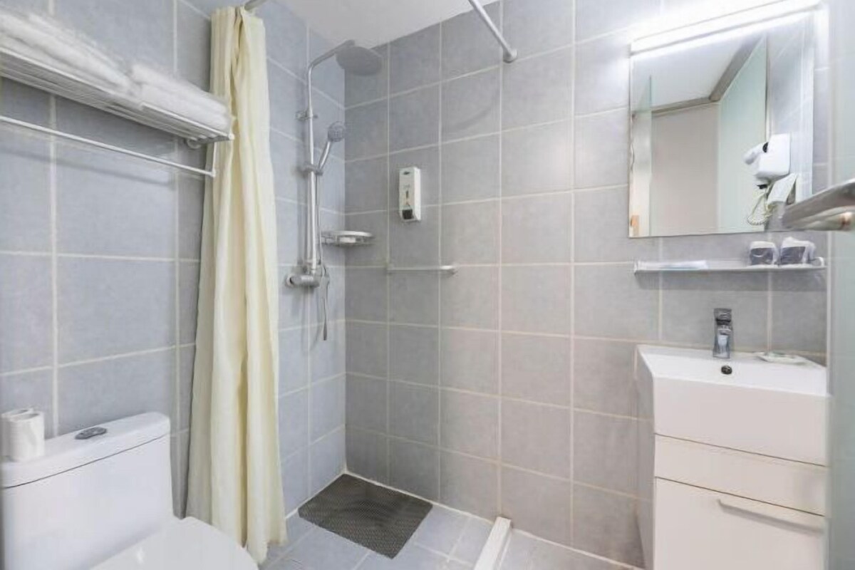 A bathroom with a shower, toilet, sink, and a mirror.