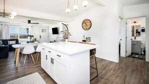 Una cocina moderna con armarios blancos, una isla central e iluminación colgante.