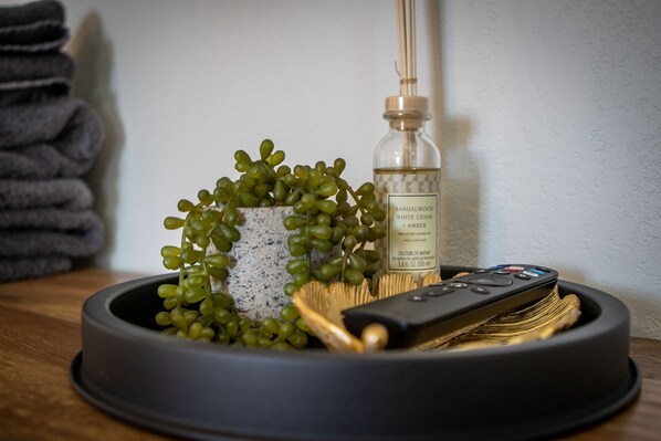 A remote control, a bottle of essential oil, and a small potted plant on a tray. - Large HotTub, King Bed, Nintendo 64, Arcade (Twentynine Palms)