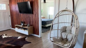 Una sala de estar moderna con un sillón colgante, pared de paneles de madera y un televisor de pantalla plana.