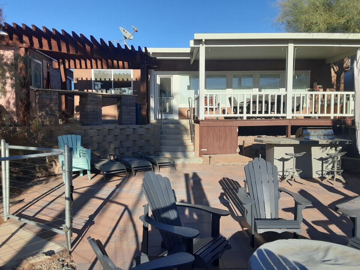 An outdoor patio area with Adirondack chairs, a barbecue grill, and a covered seating area.