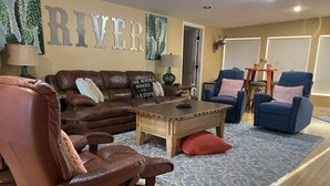 Una sala de estar con un sofá de cuero marrón, un sillón azul y una mesa de centro.