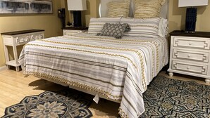 Un dormitorio con una cama, dos mesitas de noche, un cabecero y alfombras estampadas.