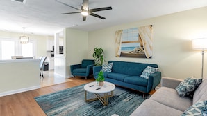 A modern living room with a teal sofa, a grey sofa, a round coffee table, and a ceiling fan. - 1 Block to Beach • Hot Tub • Fire Pit • Game Room (Norfolk)