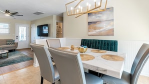 A dining area with a marble table, cushioned chairs, a chandelier, and a painting on the wall. - 1 Block to Beach • Hot Tub • Fire Pit • Game Room (Norfolk)