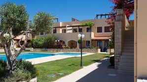 A pool area with a clear blue pool, surrounded by a well-maintained lawn and stone walls.