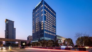 A high-rise building with a modern glass facade, a prominent sign at the top, and a well-lit entrance area. - Wyndham Changzhou Xinbei (Changzhou)