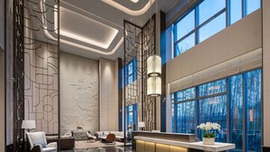 A modern lobby with a reception desk, seating area, and large windows offering views of the outdoors. - Wyndham Changzhou Xinbei (Changzhou)