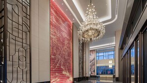 A spacious lobby with a reflective floor, a large red patterned wall, and a grand chandelier. - Wyndham Changzhou Xinbei (Changzhou)
