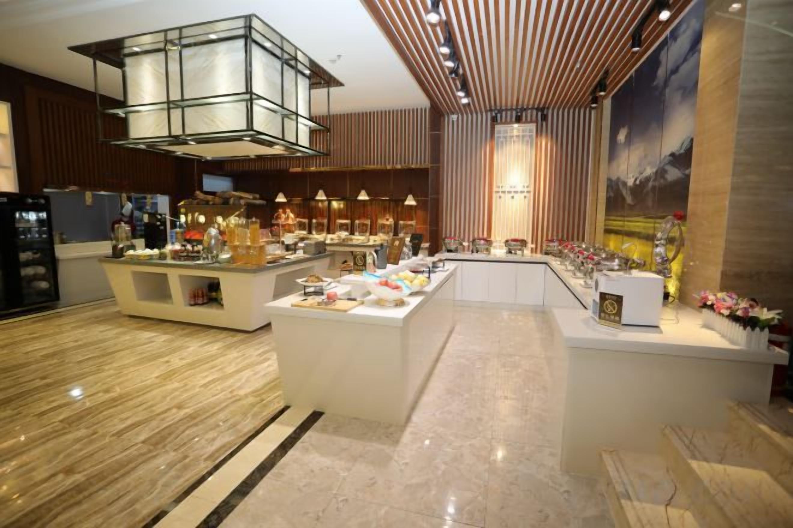 A modern hotel lobby with a central bar area, seating, and a large decorative light fixture.