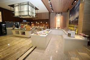 A modern hotel lobby with a central bar area, seating, and a large decorative light fixture. - Putong Hotel (Xining)